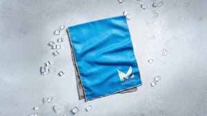 Blue cooling towel with the Mission logo amidst ice cubes, evoking refreshing comfort and peak performance.