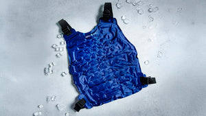 Deep blue Alpha Cool cooling vest surrounded by melting ice cubes on a cool grey surface, highlighting refreshing relief.