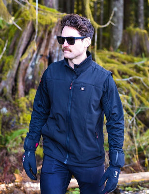 Black men's softshell battery heated vest by ActionHeat, with a red zipper pull and glowing chest logo, worn outdoors.