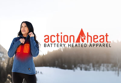 A woman in a blue heated top stands in a snowy forest. Red panels on her chest illustrate the 