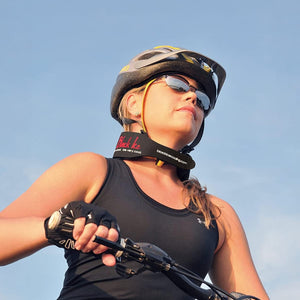 A woman in a cycling helmet, sunglasses, and black tank top rides a bike, looking upward. A black "Black Ice cooling" neckband with "blackicecooling.com" is visible against a blue sky.