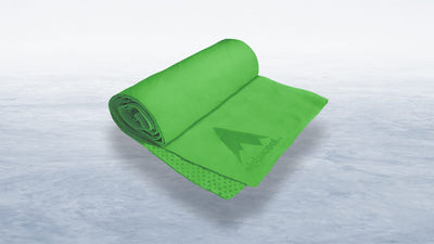 A bright green Alphacool towel, partially rolled and unfolded, with a mountain logo, rests diagonally on a textured white and light blue surface.