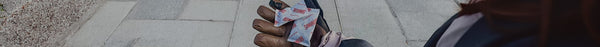 A person wearing a brown leather glove holds multiple white packets of 
