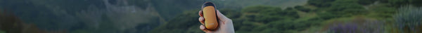 A hand holds an orange and black oval device with 