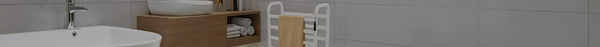 A modern bathroom featuring a white tub, wooden vanity with a vessel sink and towels, and a white towel warmer against light grey tiled walls.