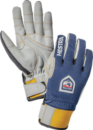Pair of blue fabric and light gray leather gloves by Hestra, featuring yellow accents, adjustable wrist straps, and brand logos.