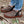 Brown felted bootie slippers by Acorn, featuring an embroidered owl and white zig-zag stitching, worn on a wooden deck.