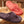 Azalea Women's Spa Thong Slippers by Acorn, a fuzzy terrycloth pair in Azalea and dark grey on wood.