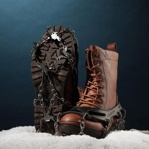 Silver and black ice cleats by Action Traction, featuring metal chains and spikes, on brown leather boots in snow.