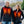 Black softshell men's heated vest by ActionHeat, featuring red glowing zones and yellow heating elements, worn by two smiling people.