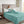 King size teal microlight heated blanket by Beautyrest, with a subtle striped texture, draped over a bed with a woman reading.
