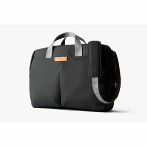 Dark gray fabric work bag by Bellroy with light gray handles, a shoulder strap, and a brown leather logo tag.