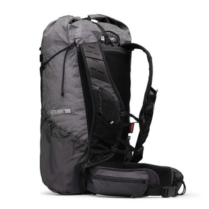 Grey grid pattern Beta Light 30 backpack by Black Diamond, featuring a bungee cord, mesh side pockets, and a padded hip belt, shown from a side angle.