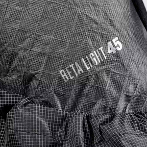 Dark grey Beta Light 45 backpack by Black Diamond, with silver text on fine woven ripstop fabric and a white grid pattern on the gathered bottom.