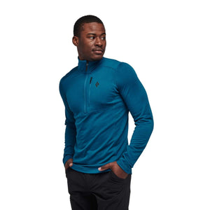Teal men's quarter zip pullover by Black Diamond, featuring textured fabric, a chest pocket with diamond logo, worn by a man in black pants.