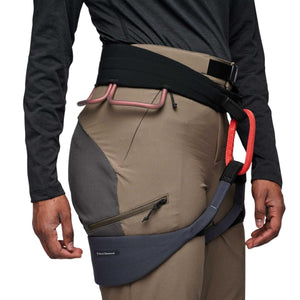 Taupe and dark grey Women's Alpine Hybrid Pant by Black Diamond, with a zippered thigh pocket, worn with a climbing harness.