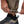 Khaki Women's Alpine Hybrid Pant by Black Diamond, with hands adjusting the elastic drawcord cuffs above a dark shoe.
