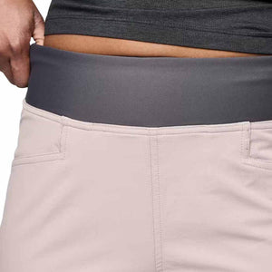 Women's light pink Alpine Light Pant by Black Diamond, featuring a dark grey elastic waistband pulled by a hand.