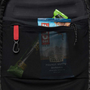 Black women's Distance 22 backpack by Black Diamond, close-up of an open internal mesh pocket with energy bars, carabiner, and red loop.