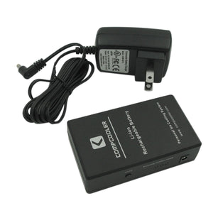 Black handheld cooling system by CompCooler with visible labels, next to its battery charger.
