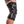 Black knee sleeve by DonJoy with white stripe, hexagonal logos, and adjustable straps, worn on a bent leg.