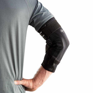 Black elbow brace by DonJoy, with visible straps, protective padding, and white logos, worn on a person's arm.