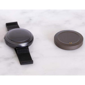 Dark gray Embr Wave 2 wearable device by Embr Wave with black mesh band and separate dark gray charging dock on marble.