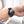 Dark gray Embr Wave 2 wearable device by Embr Wave, with a round face and black mesh strap, on a wrist.