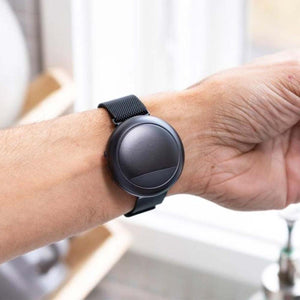Dark gray Embr Wave 2 wearable device by Embr Wave, with a round face and black mesh strap, on a wrist.