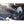 Black portable misting fan by ExtremeMIST with multiple nozzles spraying a fine mist in a truck bed.