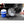 Advanced Portable Misting Fan Pro, black, by ExtremeMIST, spraying mist in a truck bed next to a blue cooler and a hand holding a remote.