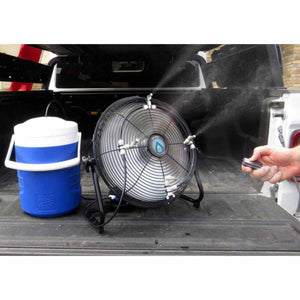 Advanced Portable Misting Fan Pro, black, by ExtremeMIST, spraying mist in a truck bed next to a blue cooler and a hand holding a remote.