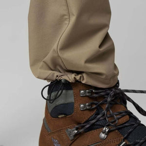 Khaki stretch trousers by FjallRaven with a cinched ankle hem and black cord, worn over a brown hiking boot.