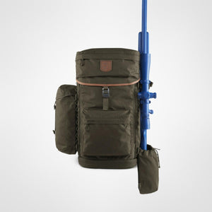 Dark olive robust backpack by FjallRaven with brown leather trim and a blue toy rifle strapped to its right side, supported by a matching pouch.