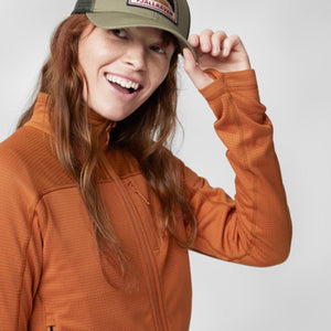 Orange textured full-zip fleece jacket by FjallRaven with thumbholes, worn by a smiling woman.