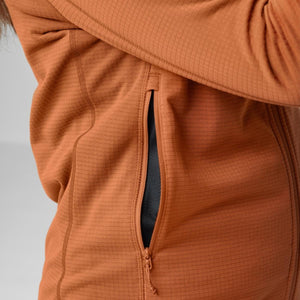 Orange women's fleece jacket by FjallRaven with a subtle grid pattern and a partially unzipped side pocket.