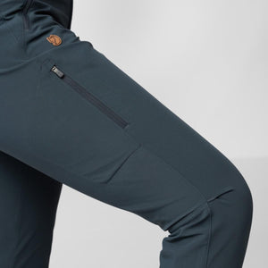 Dark teal Women's Abisko Trail Stretch Trouser by FjallRaven, featuring a zippered thigh pocket and fox logo patch.