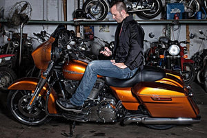 Black heated jacket liner by Gerbing worn by a man on an orange motorcycle.