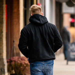 Men's black heated hoodie by Gobi Heat, seen from the back on a man walking in blue jeans.