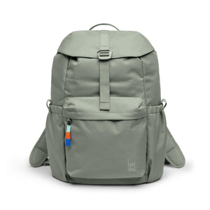 A sage green flap pack backpack by Got Bag, featuring a buckle closure, front pocket, and colorful zipper pull.