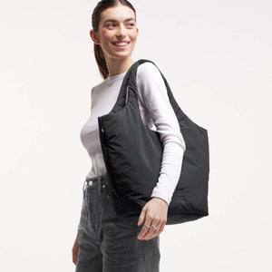 Black padded tote bag by Got Bag, carried over a woman's shoulder, wearing a white long-sleeve top.