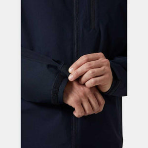 Navy blue men's hooded midlayer jacket by Helly Hansen, with a hand adjusting the black velcro cuff.