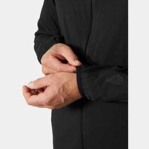 Black insulator jacket by Helly Hansen with an Odin logo on the sleeve, shown cropped as a person adjusts the cuff.