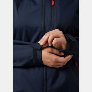 Navy blue women's crew jacket by Helly Hansen, shown cropped with a person adjusting the cuff's velcro strap.