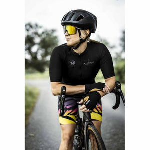 Black and tan short 5-finger gloves by Hestra, worn by a cyclist on handlebars, with 'HESTRA' text visible.