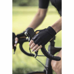 Black fingerless cycling gloves by Hestra with tan palm accents, worn by a person gripping bike levers.