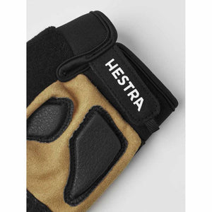 Black and tan short 5-finger gloves by Hestra with textured black palm pads and a white HESTRA logo on the wrist strap.