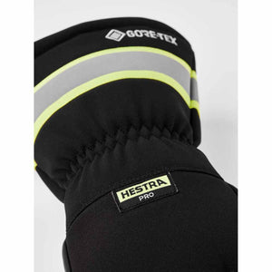 Close-up of a black five-finger glove by Hestra with reflective gray and neon yellow stripes, and Gore-Tex and Hestra Pro labels.