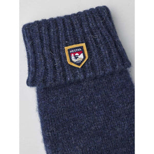 Navy blue wool mittens by Hestra, with a shield logo patch and ribbed cuff.