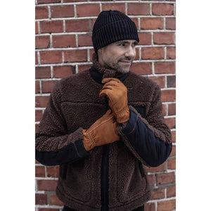 Brown nubuck leather gloves by Hestra with visible stitching, worn by a man in a brown fleece jacket.